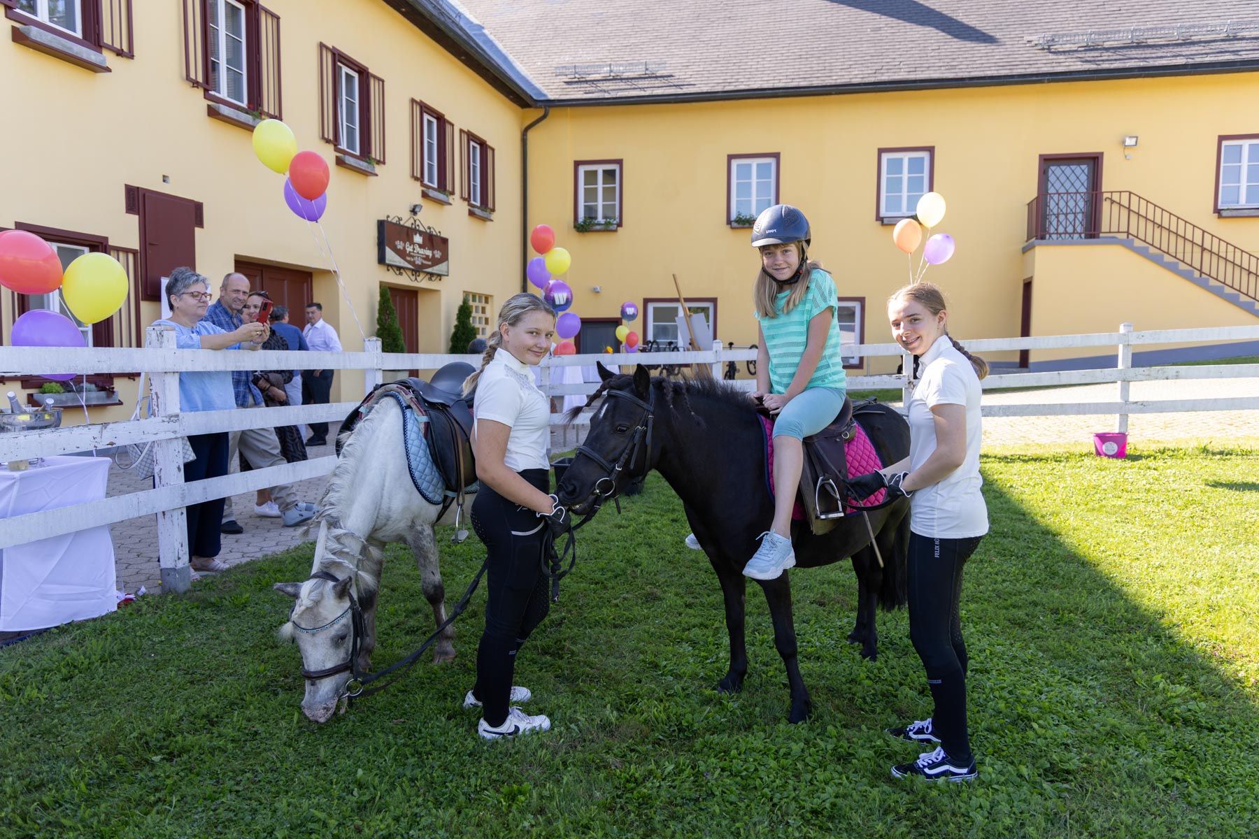 Zwei Ponys geführt von jugendlichen Reiterinnen und eine Besucherin die das Ponyreiten ausprobiert.